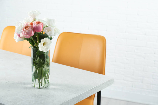 Vase with beautiful flowers as element of interior design on table in room. Space for text - 写真・画像