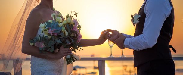 Nowożeńcy, trzymając się za ręce o zachodzie słońca - Zdjęcie, obraz