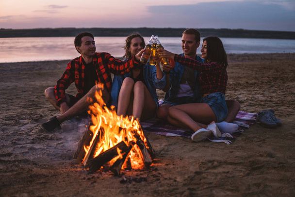 young friends have picnic with bonfire on the beach - Photo, Image