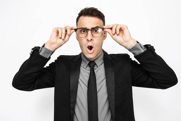 Business handsome man in glasses and suit, amazingly shocked with big eyes and open mouth, isolated on white background - Фото, изображение