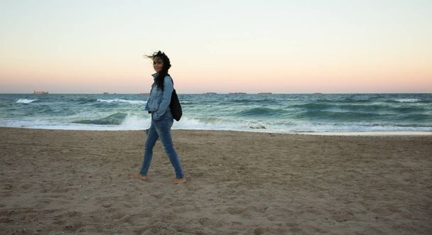 Woman with jeans and denim jacket, walking on a beach in Valencia, Spain - Foto, Imagem