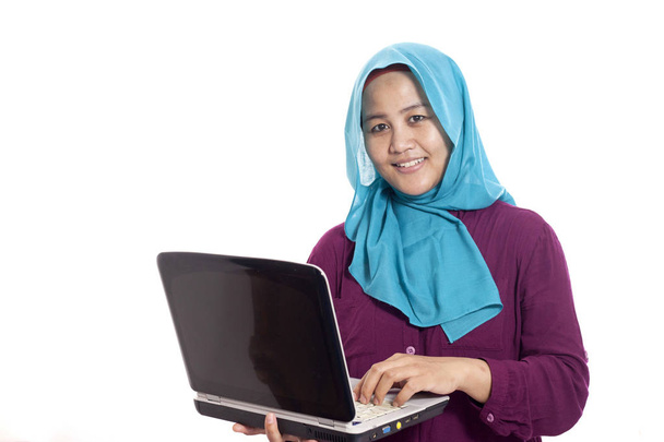 Portrait of happy successfull muslim business woman wearing hijab smiling while typing on her laptop, isolated on white - Foto, afbeelding