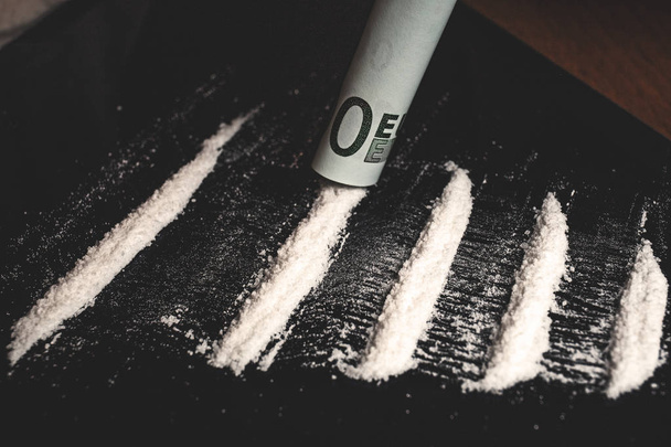 Drugs verslaafde briezende lijnen van cocaïne of metamfetamine poeder narcotic met opgerolde biljet - Foto, afbeelding