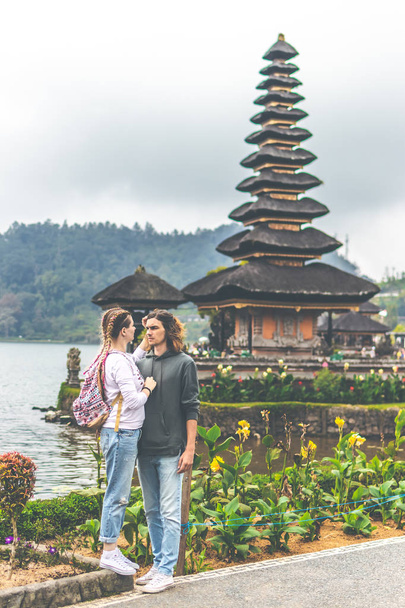 Young romantic couple of trourists on the Ulan Danu temple background. Bali island. - Photo, Image