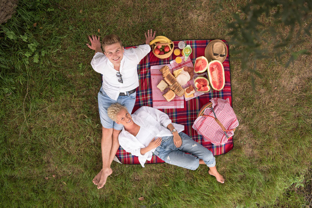 Couple in love enjoying picnic time while sitting on plaid - Foto, Bild