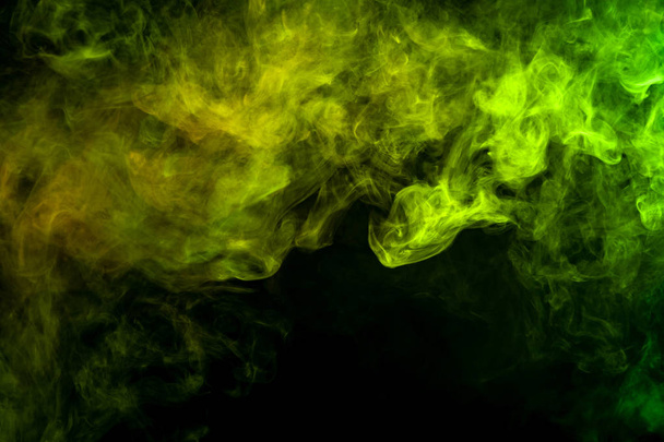 Textural background for creativity. Colorful green and yellow smoke  on a black isolated background. Background from the smoke of vap - Foto, Imagen