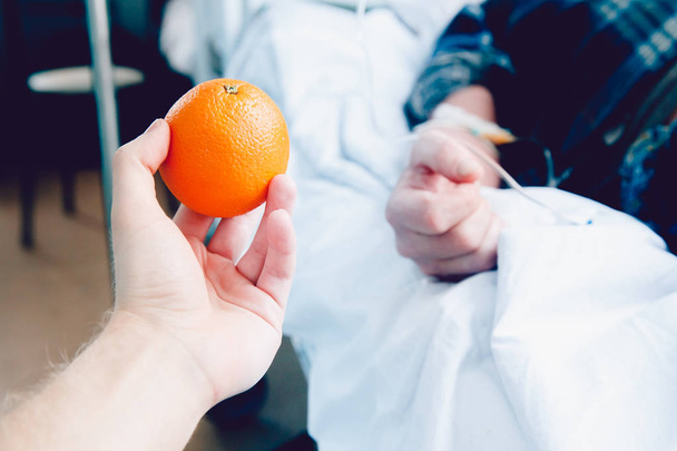 Die Hand des Arztes hält die Orange gegen den Tropfer - Foto, Bild