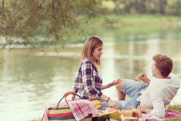 Couple in love enjoying picnic time drink and food in beautiful nature on the river bank - Foto, Bild