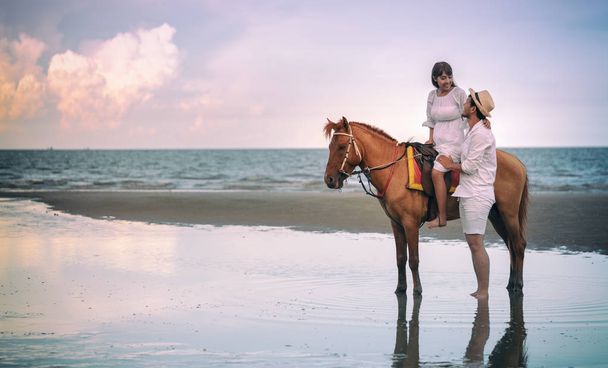 Young couple riding horse on seacoast in summer - Photo, Image