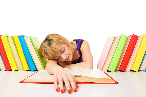 κουρασμένος από μελέτες, νεαρή γυναίκα κοιμάται στο γραφείο της με βιβλία - Φωτογραφία, εικόνα