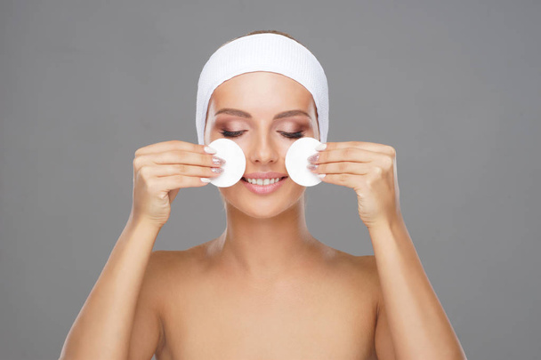 Young woman cleaning her face with a cotton pads. Girl removing cosmetics with hygienic discs. Cosmetology concept. - Photo, image