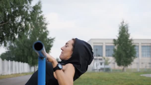 Trening fitness kobieta próbuje robić ćwiczenia na poziomej bar na świeżym powietrzu - Materiał filmowy, wideo