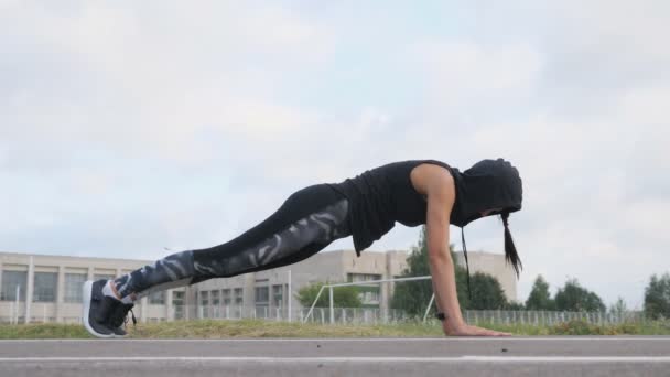 Mladá žena sportovec fitness cvičením prkno na stadionu - Záběry, video