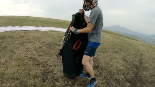 Close-up professional paraglider pilot prepares for takeoff, buttoning equipment and straightening slings - Filmagem, Vídeo