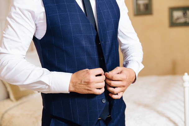 Close-up of a cropped frame of a business stylish man buttoning his jacket, standing in a stylish office with designer repair. - Valokuva, kuva