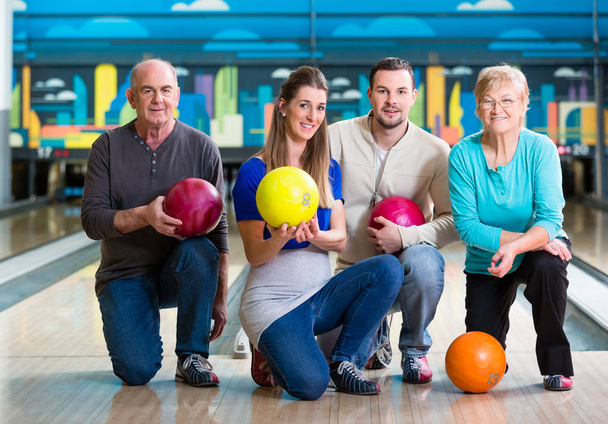 Сім'я з різнокольоровими позує на м'яч боулінгу
 - Фото, зображення