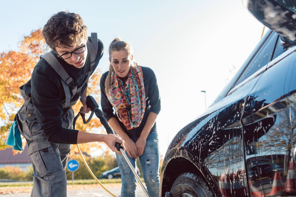Службовець допомагає жінці прибирати авто в автомийці
 - Фото, зображення