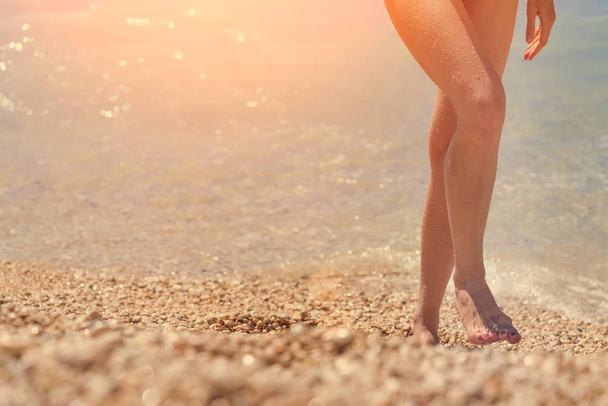 Female feet emerging from the sea  in the sunlight - Фото, изображение