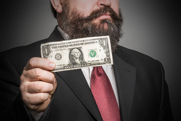 Adult bearded man in a suit holding a dollar - Фото, зображення