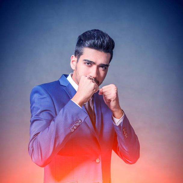 Young attractive man in a blue suit standing in a fighting stance. Toned - Photo, Image