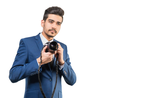 Young attractive man in a blue suit with a camera on a white background. Isolated - Foto, immagini
