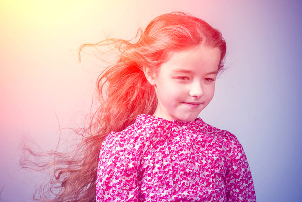 Cute little girl in a red dress with long hair in the sunlight - Fotó, kép