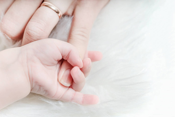 Hand of a baby holds a woman's finger - Valokuva, kuva