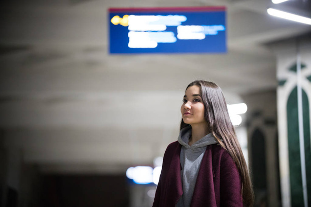 Fiatal, csinos nő várja a vonat a metróban platformot. Éjszaka. Mosolyogva - Fotó, kép