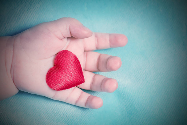 Red heart in the hand of a baby. Toned - Foto, Bild