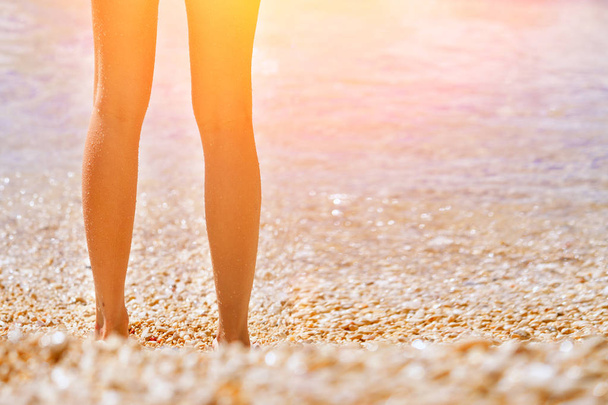 Female feet emerging from the sea  in the sunlight - Foto, imagen