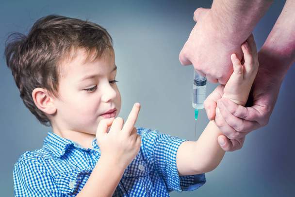Boy in the blue shirt showing middle finger during vaccination - Fotó, kép