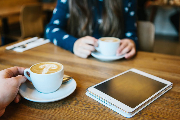 La gente disfruta de su café de la mañana en un café y se comunican entre sí. La tableta está sobre la mesa
 - Foto, imagen