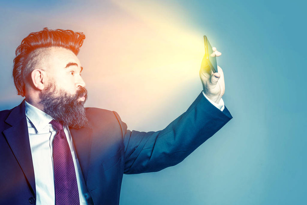 Adult bearded man in a suit makes selfie with luminous phone - Zdjęcie, obraz