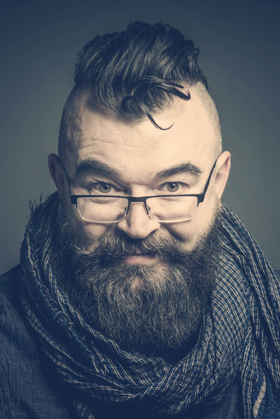 Portrait of an adult man with glasses and a scarf and with a mohawk hairstyle. Toned - Photo, image