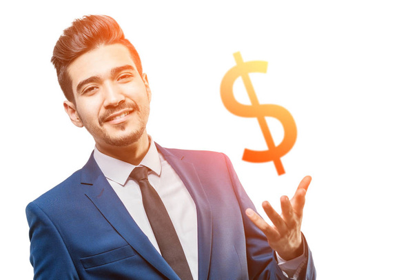 Young attractive man in a blue suit holding in the palm of your hand orange dollar sign in the sunshine on a white background - Fotoğraf, Görsel