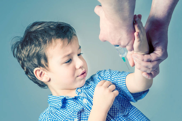 Scared boy in the blue shirt  during vaccination - 写真・画像