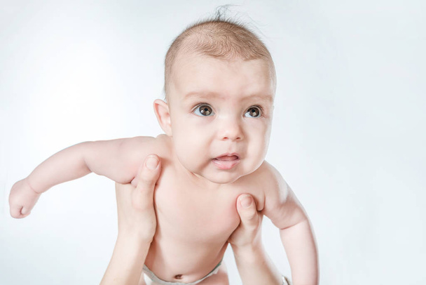 Cute baby in female hands on a white background - Foto, imagen