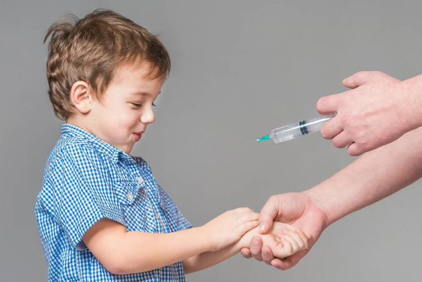 Boy in the blue shirt are vaccinated on a gray background. Isolated - Foto, imagen