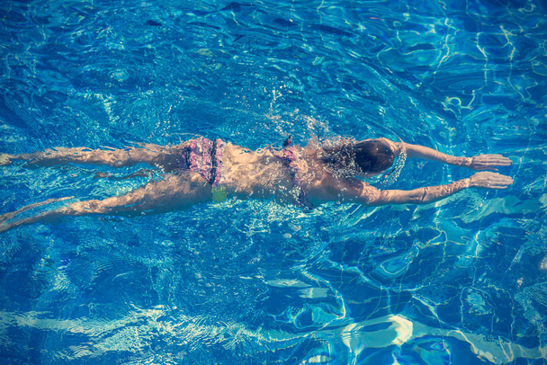 Woman in bikini swims in the pool - Φωτογραφία, εικόνα