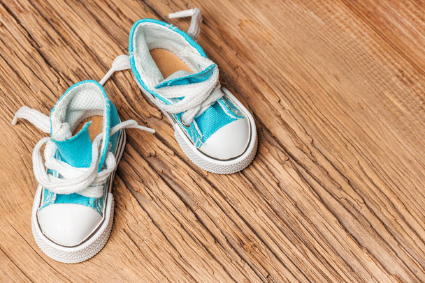 Toy blue sneakers on old wooden surface - Photo, Image