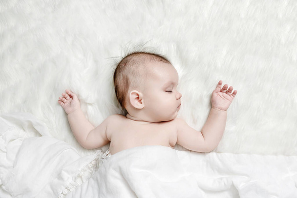 Cute baby sleeping on a white fluffy background - Фото, изображение