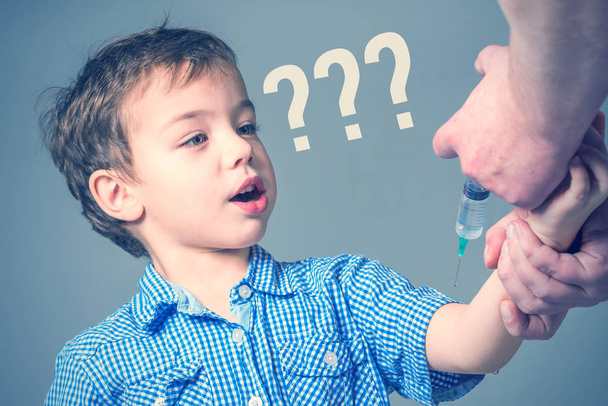 Boy in the blue shirt  during vaccination with question mark - 写真・画像