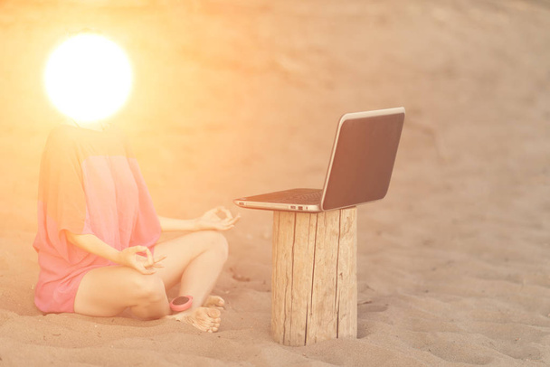 Girl with glowing head meditating in front of a laptop at the beach - Fotoğraf, Görsel