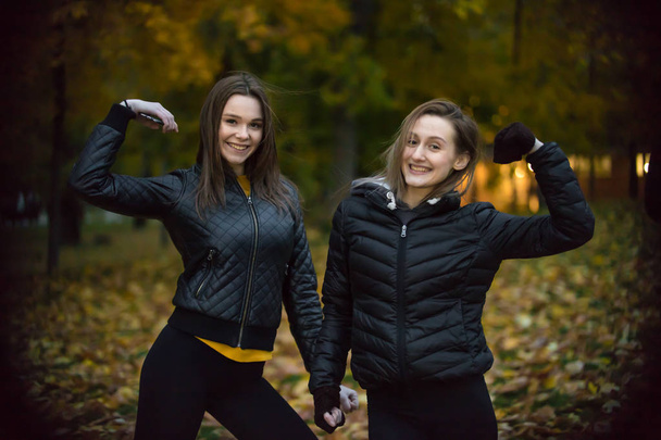 Porträt zweier Mädchen in schwarzen Jacken im Herbstwald - Foto, Bild