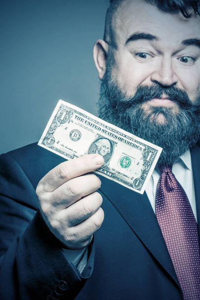 Adult bearded man in a suit  holding a dollar - Foto, Imagen