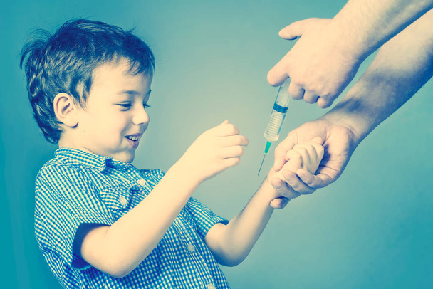 Boy in the blue shirt are vaccinated on a blue background. Toned - Foto, imagen