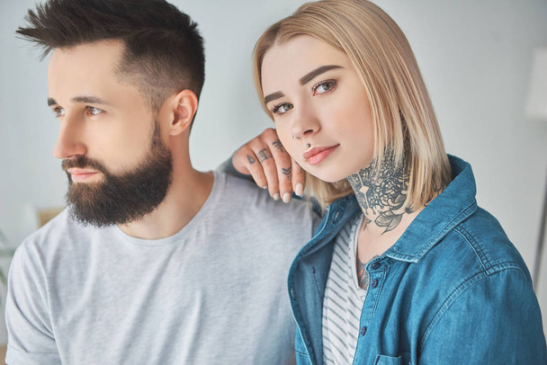 beautiful tattooed girl standing with boyfriend and looking at camera - Photo, Image