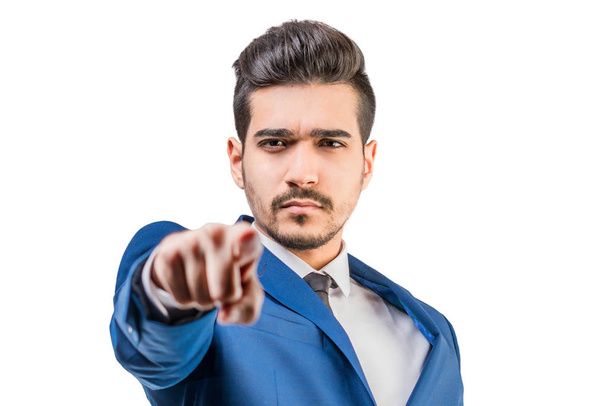 Young attractive man in a blue suit showing a finger forward on a white background. Isolated - 写真・画像