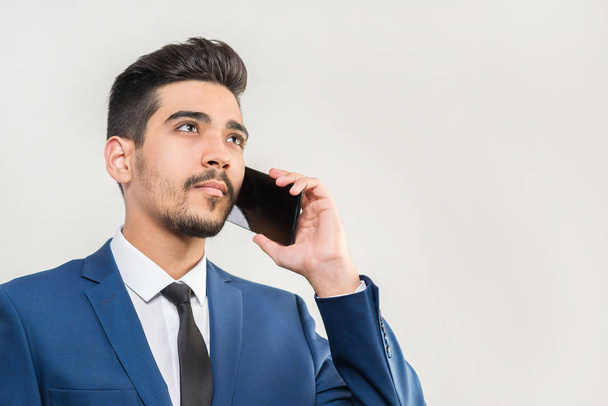 Telefonun yanında gri bir arka plan üzerinde konuşmak mavi elbiseli Genç çekici adam. İzole - Fotoğraf, Görsel