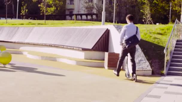 Um homem em um terno de negócios montando uma scooter pontapé
 - Filmagem, Vídeo